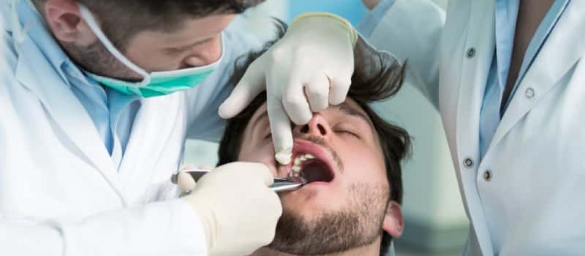 Dentistry education. Male dentist doctor teacher explaining treatment procedure to students group in dental clinic.